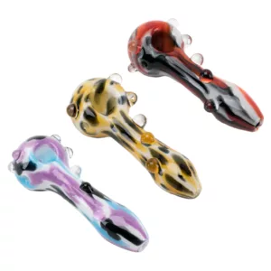 Two colorful, psychedelic glass pipes with curved handles and spoon or rectangular shapes, shot from above on a white background.
