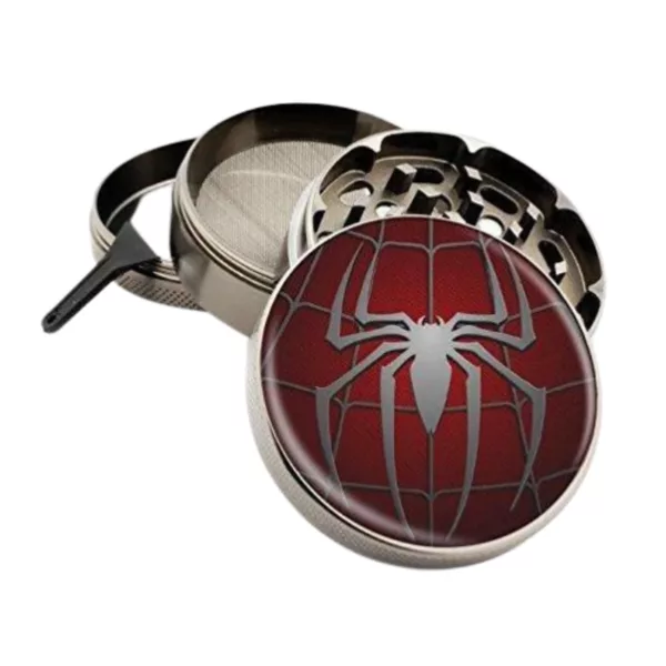 Spider emblem grinder with black and white web design, silver metal body, and small circle release mechanism.
