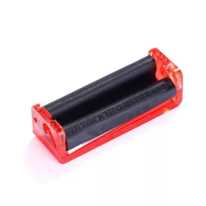 Red plastic rolling machine with black handle and clear lid, rectangular shape with small hole. Sitting on white background.