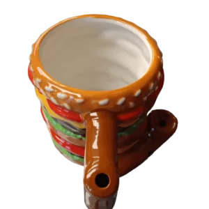 A ceramic mug with a handle and brown/orange design, sitting on a green surface.