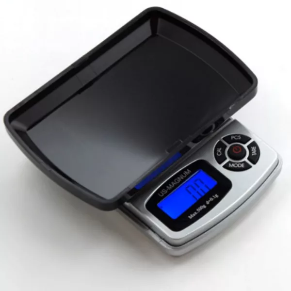 portable, electronic scale used to measure weight in grams or kilograms. It has a clear glass surface and metal base with two weighing pans, and is battery operated with the option to recharge.