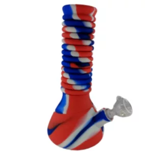 The Extendable Silicone Water Pipe features a red, white, and blue striped design and is made of clear silicone. It has a clear glass bowl and stem, and sits on a white base with the same striped design. The pipe is extendable for added convenience.