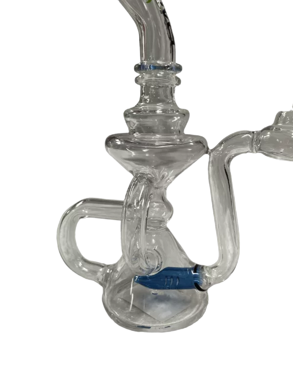 Glass bong with blue handle and clear base. Two bowls connected by clear tube. Base has small hole at bottom. Sitting on green surface.