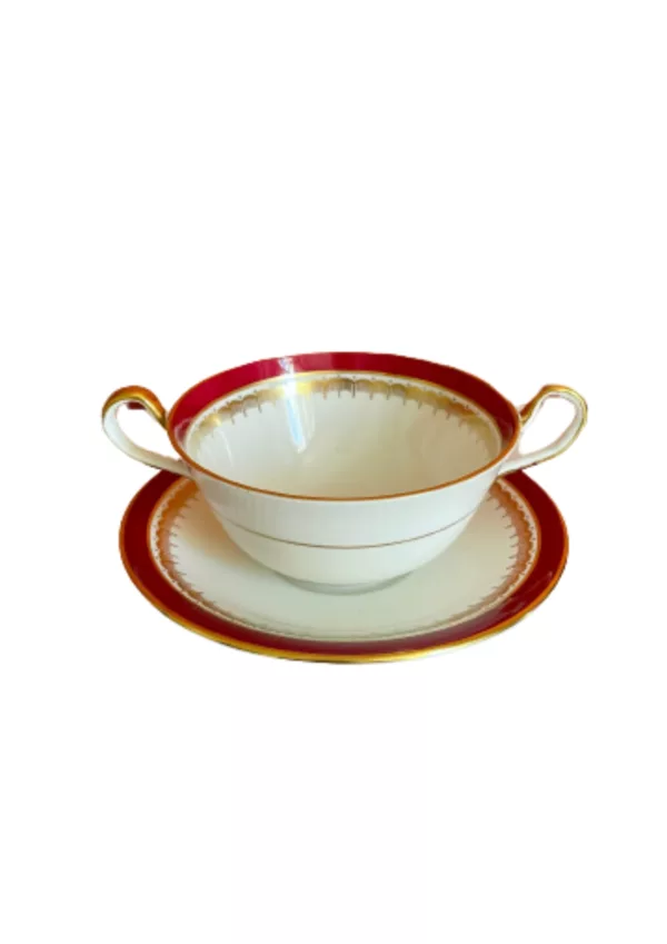 Red and white bowl with gold rim and white interior, sitting on white saucer. NN73514.