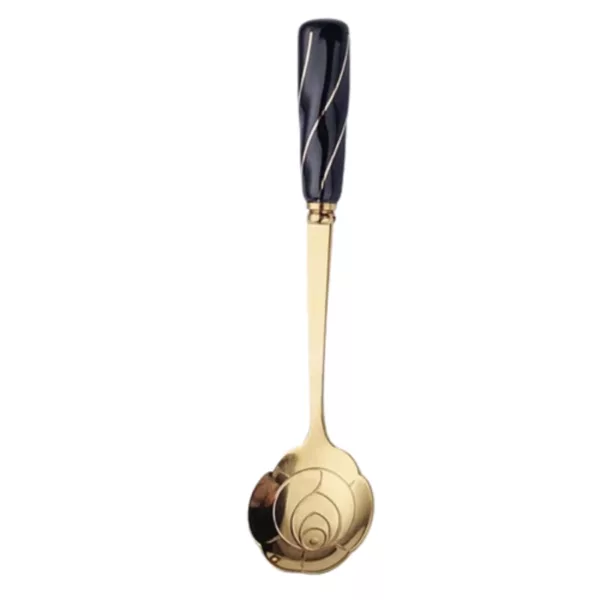 Gold-plated spoon with black handle and white background. Curved handle and small bowl decorated with black and white stripes. Used for serving or stirring.