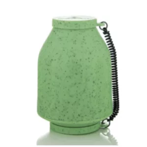 Small green glass jar with metal cap and black zipper on a white surface.
