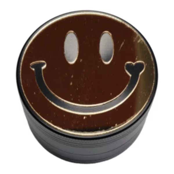 Metal grinder with black/silver design, brown smiley face on front and back, small wheel on top.