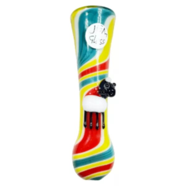 A colorful glass pipe with a playful, whimsical design featuring a black cat with closed eyes and an open mouth, sitting on top of the pipe with its tail sticking out of the small hole at the end. The pipe has a swirled design in blue, green, and yellow.