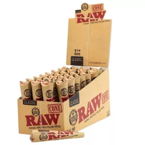 A box of raw rolling papers made of cardboard with a clear plastic window on the front. The box is brown with a white label that reads Raw Rolling Papers. The rolls are tightly packed in brown paper and stacked on top of each other. White background.
