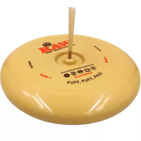 Yellow flying disc with stick on top, round and flat with small hole. Stick points up, disc lays on side.