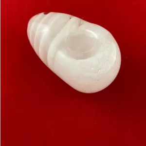 Translucent, round object with smooth surface on red surface. MLCOOCON Coocon Pipe.