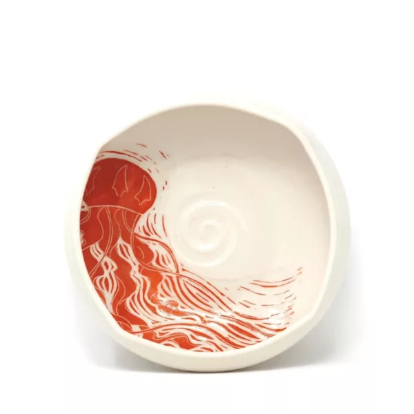 round white bowl with red and orange swirls on it, featuring a smooth surface and curved lines. It is sitting on a white surface.