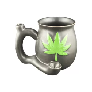 The Matte Black Mug With Green Leaf from Roast And Toast features a green marijuana leaf design on a metal mug with a handle. It is sitting on a white background.