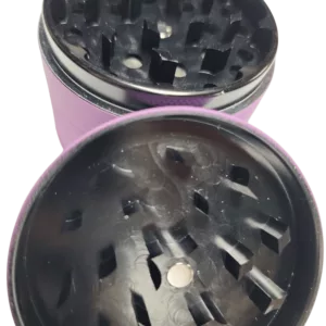 purple plastic grinder with a clear lid and black base. It has a small opening and hole, and sits on a green surface.
