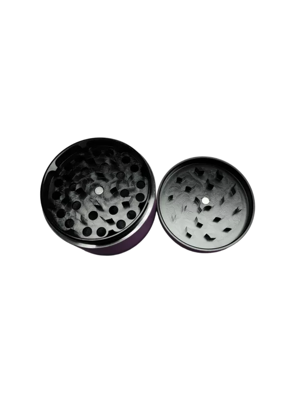 Black metal grinder with circular shape, small hole in center, and smooth surface for grinding herbs and spices into a fine powder.