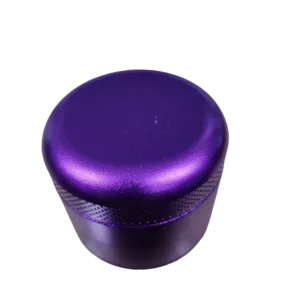 A purple and black grinder with a metal casing, clear plastic insert, and small button on the side. No brand or label visible.