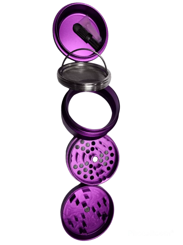 A purple metal grinder with clear lid and black base on a green surface.