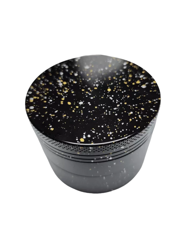 Round black and gold glittery bowl with starry pattern. Smooth surface, sits on green background.