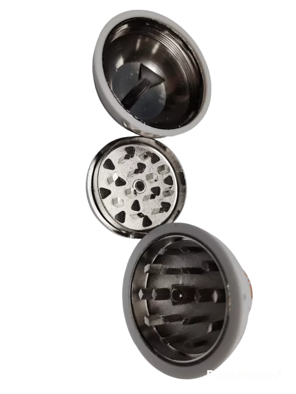 Small grinder with cylindrical body and rotating drum teeth for crushing herbs. Metal cover on one end.