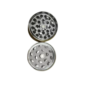Black grinder with circular metal plate, small knobs/buttons, and metal handle for smoking/rolling tobacco. Silver rim around plate edge.