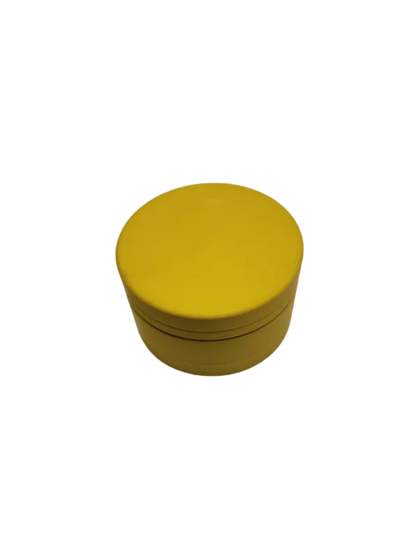 A round, yellow plastic container with a smooth surface and a lid with a small hole in the center. It sits on a green background.