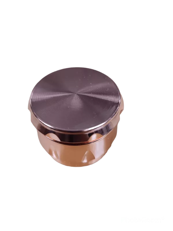 A sleek, modern aluminum Crome 3 Chamber Grinder with a round shape, flat top, and four legs for stability. It has a brown color and a small hole in the center of the top.