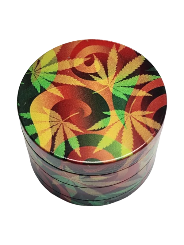 Metal grinder with colorful marijuana leaf design in green, yellow, and red. Round shape with flat bottom and raised top. Smooth surface and sits on black background.