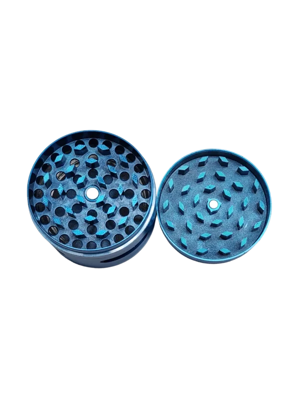 Blue & silver labyrinth grinder with small circular shape and multiple holes for herb grinding. Handle for easy use. Close up on green background.