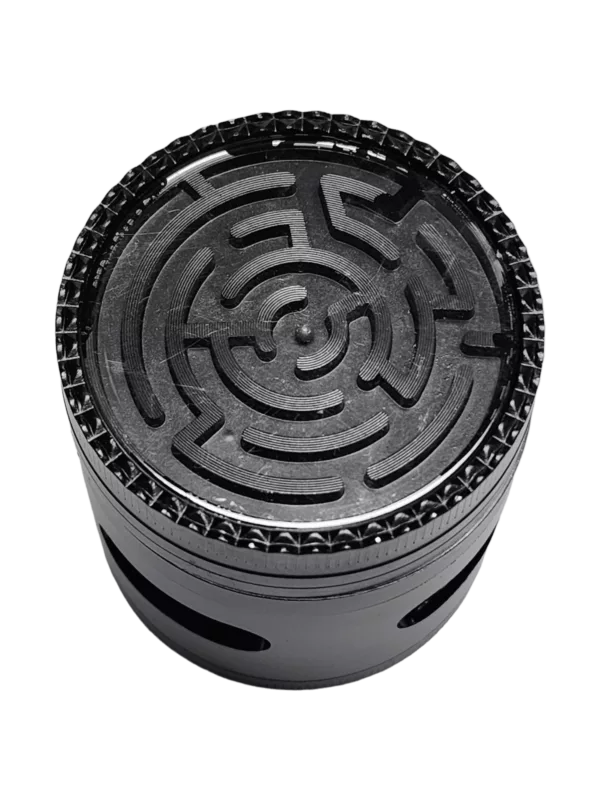 Black and white maze-themed grinder with metal casing and clear plastic lid. Features small compartment for accessories. Designed for stability on tile surfaces.