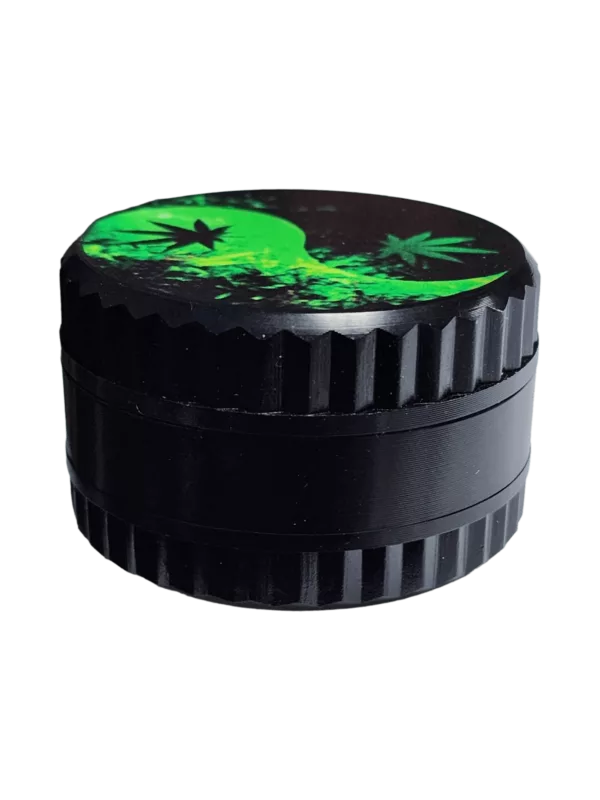 Small black plastic grinder with green design, round shape, small handle, and top opening for herb grinding. Designed for easier smoking.