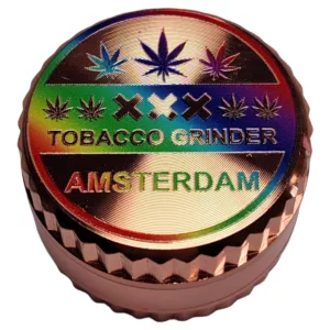 Shiny, polished metal grinder with 'Amsterdam Grinder-BVGS275R' engraved in copper on a round, flat base with a handle.