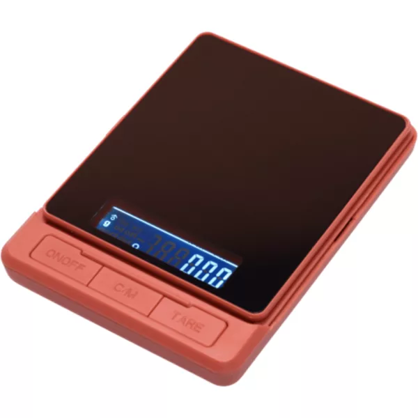 A small, red electronic scale with a black display shows weight in grams and has a smooth surface with slightly curved sides. No buttons or controls are visible.