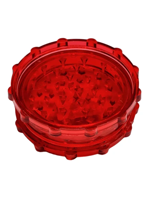 A red acrylic grinder with metal base and handle, featuring a perforated top for easy use.