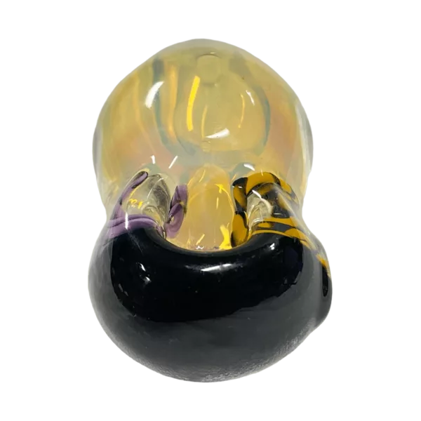 Small, round glass bead with a yellow and black color scheme and a smooth surface. Features a small hole in the center and a metallic, reflective appearance. Sits on a green background.