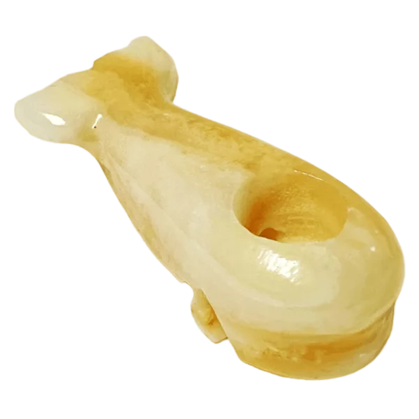Small yellow plastic or resin object with curved shape and small hole in the middle, sitting on green background - Stone Whale - Mystic.
