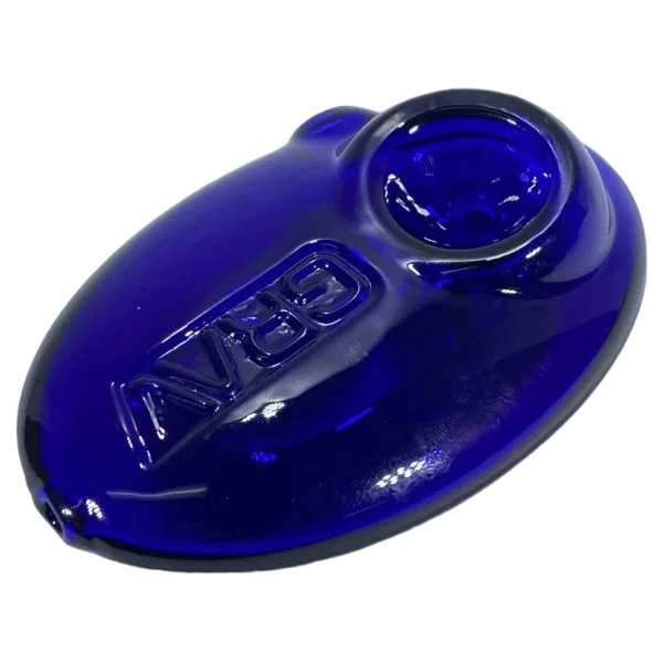 A small, clear glass ashtray or pipe with a depression shaped like a pebble and a slightly raised rim. It is about 3 cm in diameter and 5 cm tall.