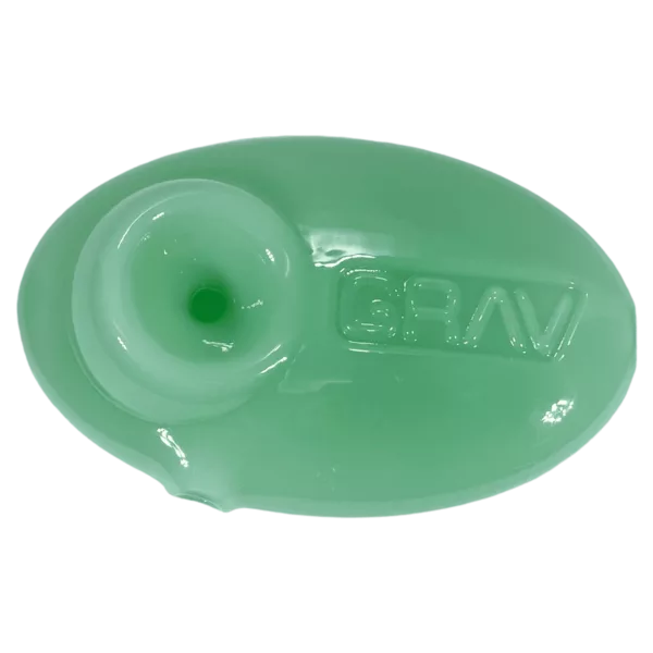 Green plastic dish with small hole in center, sitting on green surface. Not in focus.