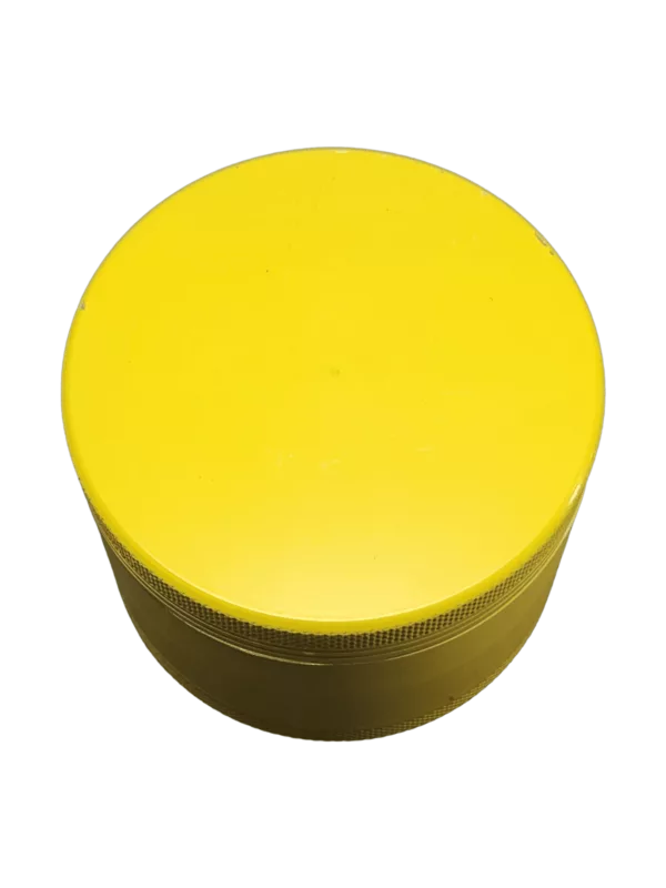 Round, smooth yellow plastic grinder with flat bottom and green background.