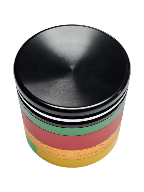 Round container with striped lid for dabbing and grinding, on green background.