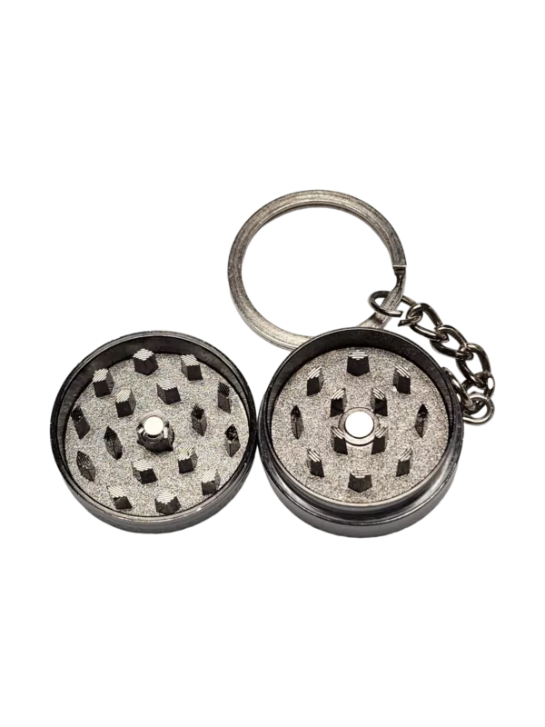 Metallic grey keychain grinder with silver accents, circular grinder with 6 holes, and 2 metal feet.