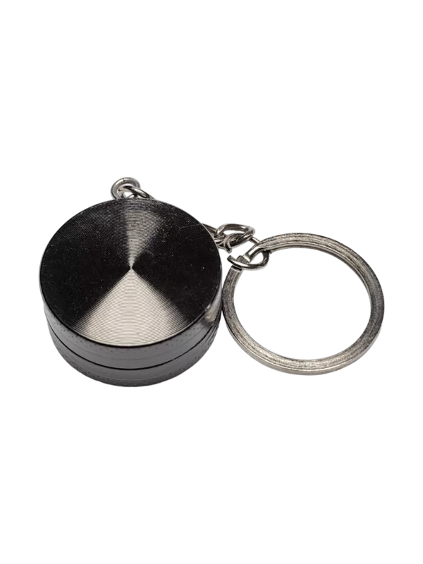 Portable keychain grinder with circular disc and sharp teeth for grinding small objects. Attaches to keyring or metal object.