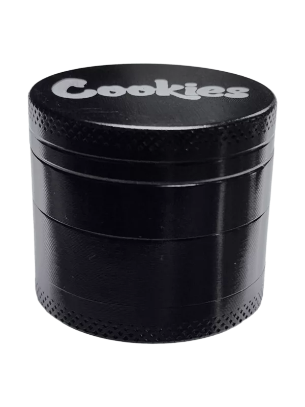 Black plastic grinder with white text and circular design. Square base, cylindrical shape, handle, and removable lid. Black and white stripe pattern on handle, small notch on lid.