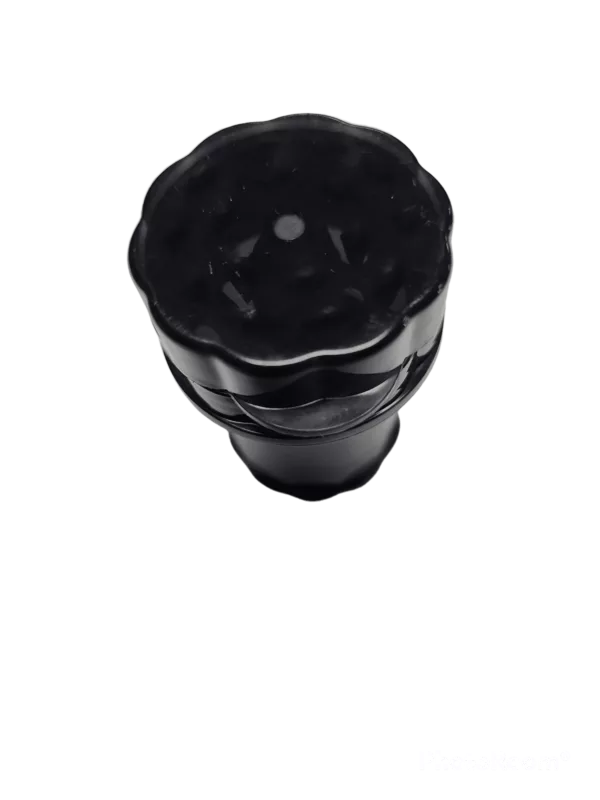 A black plastic flower-shaped grinder with curled petals, attached to a black stem with a small hole at the top and a knob at the end, sitting on a green background.